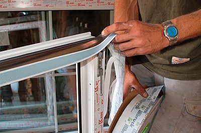 Obr. 1a, b: Nalepení interiérových (paronepropustných) a exteriérových (paropropustných) pásek na plastové okno se provádí před vsazením okna do stavebního otvoru. Na výslednou kvalitu okna mají pásky zásadní vliv, viz článek [1] v časopise Stavebnictví a interiér č. 5/2007. Někteří dodavatelé tuto operaci neprovádějí nebo od ní dokonce zákazníka odrazují. Nejenže tím mohou znehodnotit celou investici, ale jednají protiprávně, neboť použití pásek dnes odkazem na ČSN 73 0540 stavoví stavební zákon.