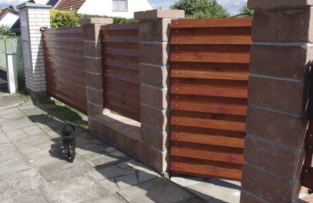 Dřevěné plotové výplně jsou často kombinovány s kamennými či 

betonovými sloupky.
V tomto případě jde o betonové tvarovky s patinou.