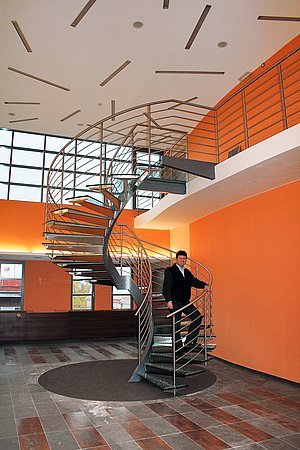 Točité schodiště se skleněnými stupni spojuje dvě úrovně víceúčelového sálu