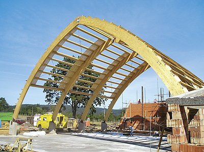 Montáž střechy sportovní haly z plnostěnných lepených zakřivených nosníků.