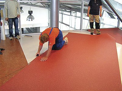 Po pokládce fólie Sigan 2 přikročili pracovníci firmy HAMED k přípravě podlahové krytiny PVC Objectfloor (rovnoběžným podélným seříznutím hran byly srovnány případné drobné deformace okrajů podlahové krytiny a sníženo vnitřní pnutí v krytině)