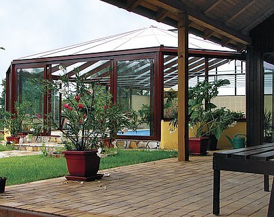 Velké prosklené plochy a konstrukce v hnědém odstínu opticky spojují interiér krytého bazénu s terasou i celou zahradou