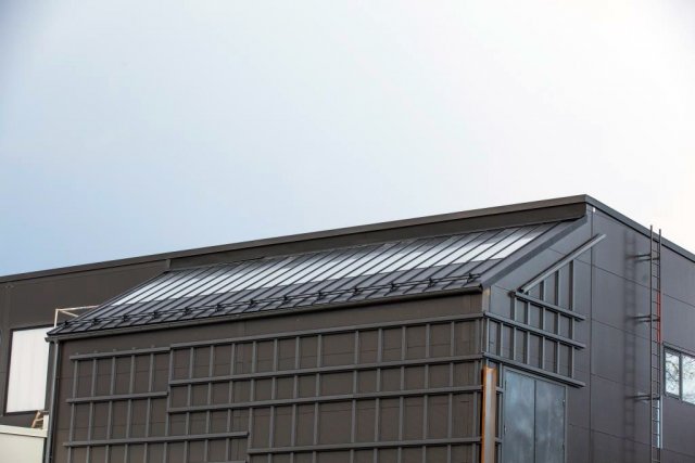 Část budovy s fasádou ze samopatinující oceli Cor-Ten. Šikmá střecha je z krytiny Ruukki Classic s plně integrovaným solárním systémem pro ohřev vody (Ruukki Classic Solar)