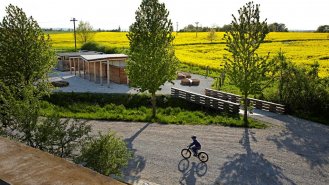 Vstupní předprostor areálu s kolárnou a občerstvením pro cyklisty od něhož vede most do areálu.