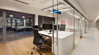 Pohled do chodby s archivem, kancelář vedení, v pozadí průzor přes atrium do skladu.