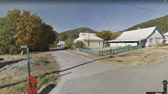 StreetView pohled z Google Maps na jednu z ulic Rosslandu s typickou zelení a světlými střechami