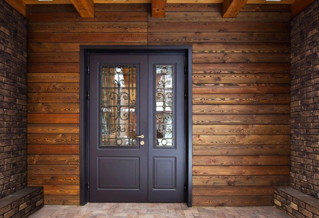 Dřevěné obložení u vchodu do domu je krásně doplněno působivými ocelovými dveřmi, které splňují všechny požadované bezpečnostní parametry. (Autor: Artserstudio. Shutterstock)