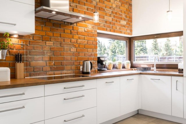 Kontrast mezi cihlovou červení a bílou kuchyňskou linkou dodává místnosti šmrnc. (Autor: Photographee.eu, Shutterstock)