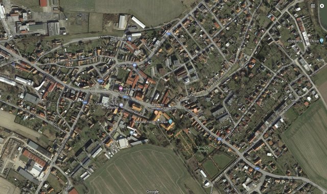 Letecký snímek Chrast (okres Chrudim), ČR (49°55’ severní šířky). S výjimkou několika málo průmyslových objektů jsou všechny střechy tmavé a takřka chybí vzrostlá zeleň, která v létě vytváří stín.