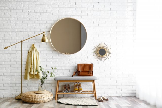 Minimalistické kulaté zrcadlo a zlatá lampa proměnily obyčejnou předsíň v oslňující místnost. Foto: New Africa