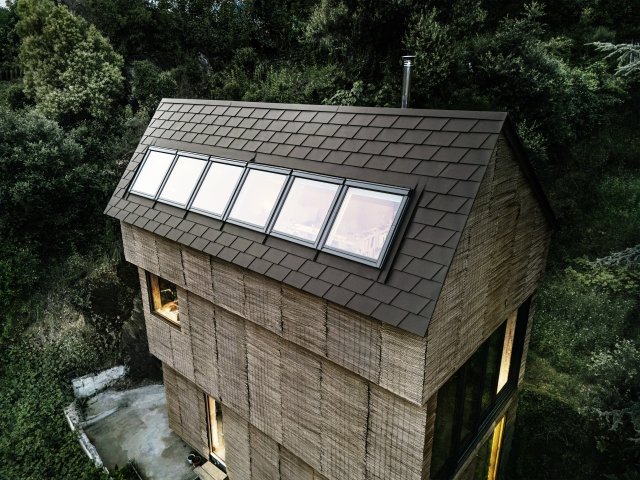  Samotný materiál krytiny je robustní, trvanlivý a nenáročný na údržbu. Zvláštním detailem je dlouhý pás oken, táhnoucí se téměř přes celou šířku střechy a přerušující šindelovou krytinu. Zdroj: PREFA Aluminiumprodukte / Croce & WIR