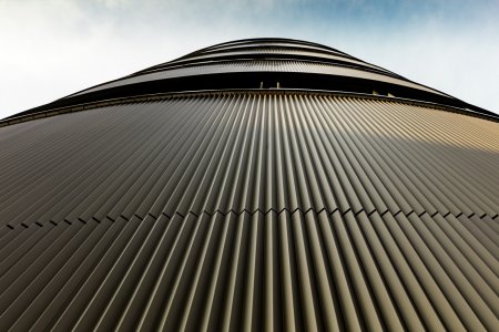 Fasádu pokrývá přibližně 1 100 m² lisovaných profilů PREFA v odstínu střední bronz C33.